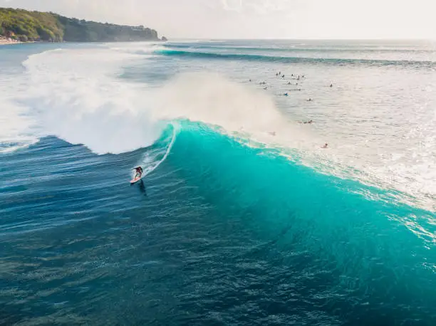 Aerial view with surfing on ideal barrel wave. Blue perfect waves and surfers in ocean