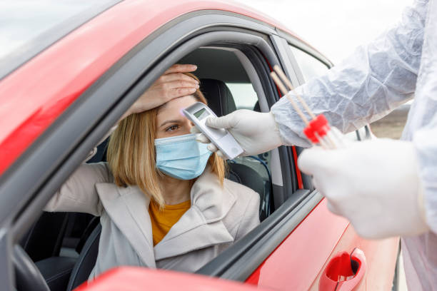 istock Medic using hand held infrared thermometer for a woman driving a car 1314366457