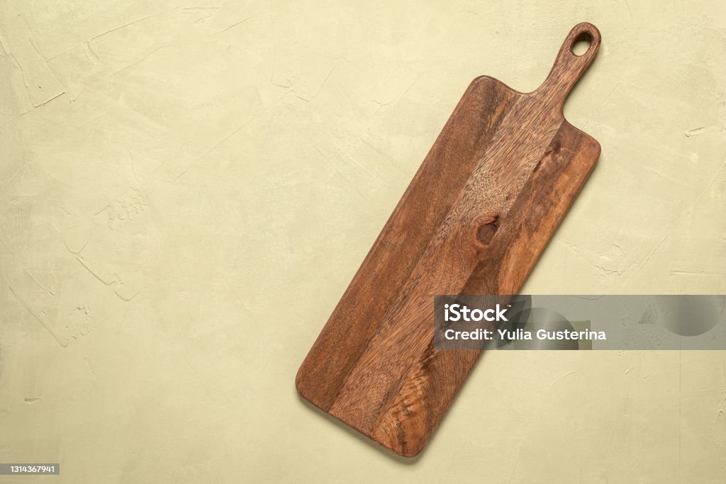 Wooden long empty cutting board on a beige concrete background. Top view, flat lay. Wooden long empty cutting board on a beige concrete background. Top view, flat lay Cutting Board Stock Photo