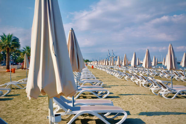 Empty beach with sun beds and unopened umbrellas waiting for the tourist to return .