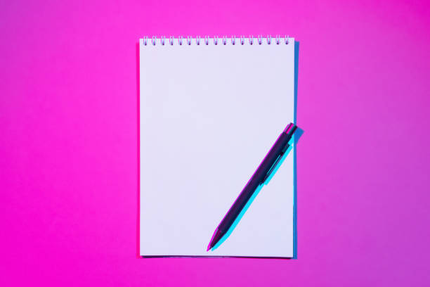 istock Blank notebook with copy space and pen on pink background. Double colorful shadows 1314369858