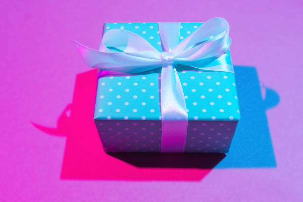 Close up of gift box on light pink background. Double colorful shadows