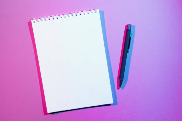 istock Blank note book and pen on pink background. Double colorful shadows 1314369922