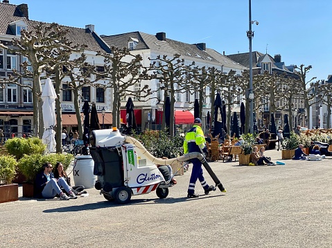 Maastricht, the Netherlands, - April 25, 2021. Public cleaner in action on the towns square during a sunny April day.