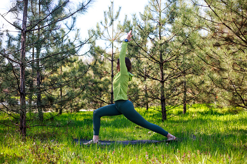 Girl doing yoga in a fir park, fitness exercise outdoors, healthy lifestyle and the freshness of pure nature