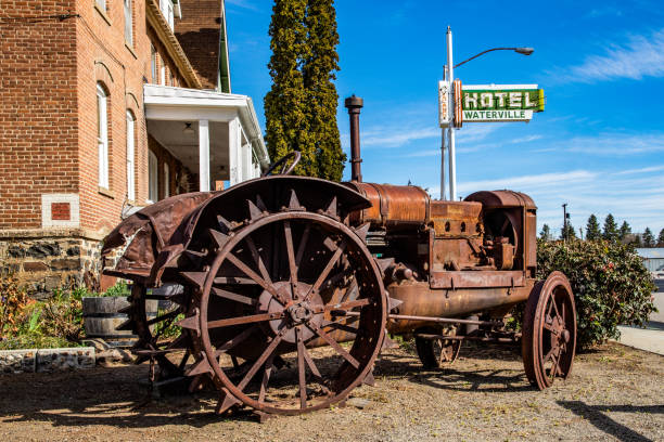 Waterville, WA. USA 04-18-2021: Old Farm Tractor, Hotel Waterville Neon Sign in Background