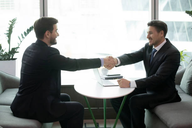istock Smiling male partners shake hands at meeting 1314375751