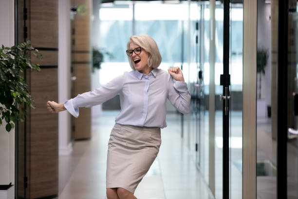 Excited middle-aged female employee dance in office