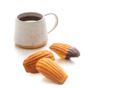 Madeleines french sponge cakes shell shaped with melted chocolate and a cup of coffee isolated on white background