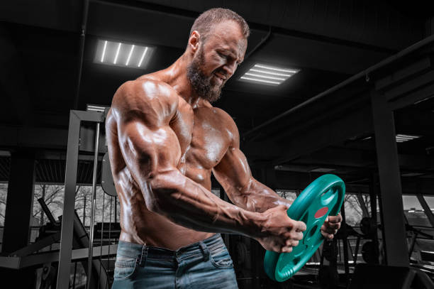Professional athlete trains with a barbell disc in the gym. Bodybuilding and fitness concept. stock photo