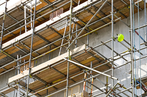 Single safety helmet hanging on the end of a scaffolding pole on a construction site. No people.