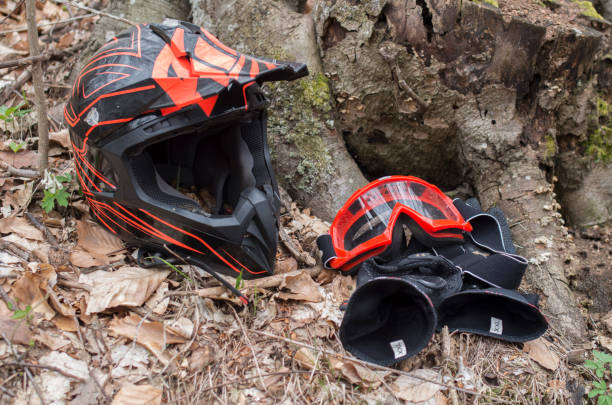 Black anf red helmet, goggles and motorcycle gloves in forest