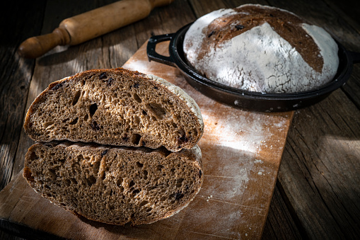 Sourdough bread loaf homemade with cast iron pan showing inner texture crumb detail on rustic wood table background with black olives