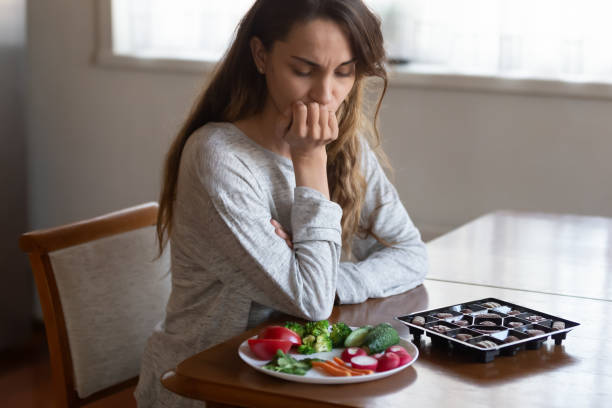 不幸な女性は健康的な不健康な食べ物の選択を考える - mental health relationship difficulties teenager divorce ストックフォトと画像