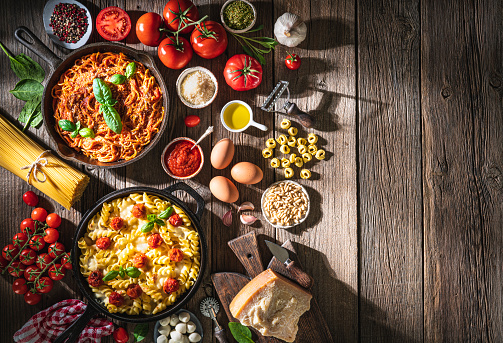 Italian food pasta recipes and ingredients as and tomato and mozzarella fusilli and spaghetti with tomato on rustic wood table  in cast iron pan