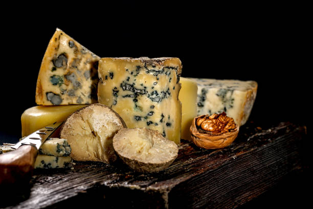 istock Assorted different luxury gourmet cheeses on a wooden board on a dark background. Various types of cheese: hard and soft with mold. Low key image. Copy space 1314383097