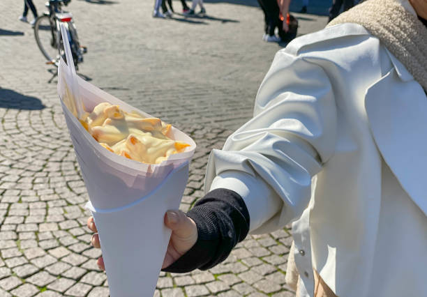 Woman is eating fresh French Fries on a sunny weekend day in Maastircht
