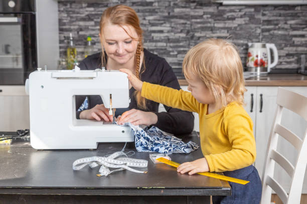 istock Young mother is sewing and her son is holding sewing machine. 1314388210