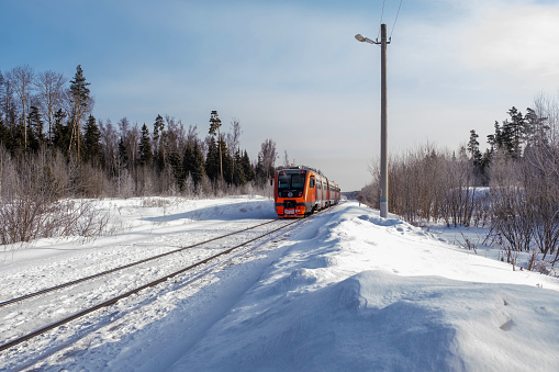 Red-orange train among white snow on a sunny winter day, Russia.