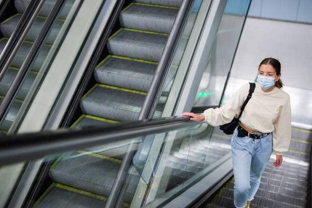 istock Young girl in protective face mask, standing on the escalator 1314389504