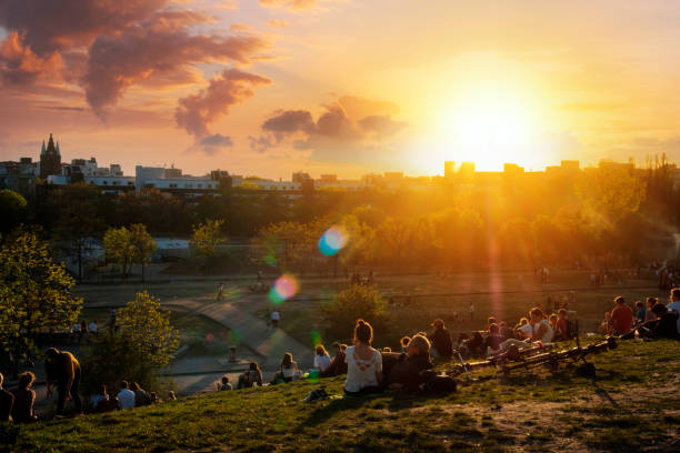 People enjoying view on sunset sky over skyline from public park (Mauerpark) on summer day in Berlin Berlin, Germany - April, 2019: People enjoying view on sunset sky over skyline from public park (Mauerpark) on summer day in Berlin teenage girls dusk city urban scene stock pictures, royalty-free photos & images