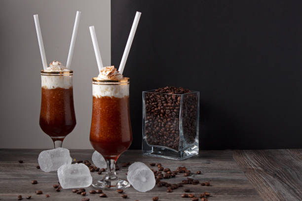 アイスクリームとコーヒーグラニータの2杯の静物のコンセプト, グラスの周りに氷とコーヒー豆と黒と白の背景にコーヒー豆でいっぱいのガラス瓶.