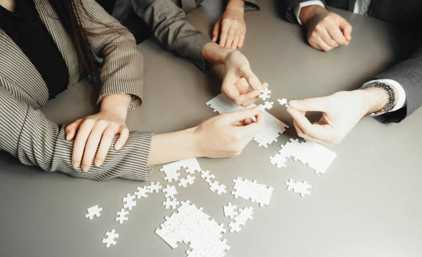 istock Business partnership or teamwork concept with a business people presenting a matching puzzle piece as they cooperate on finding an answer and solution, close up of their hands. 1314394596