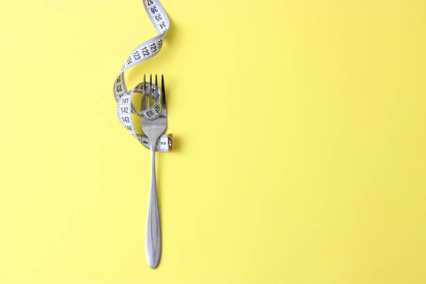 istock Measuring tape and fork on a colored background top view close-up. 1314398437