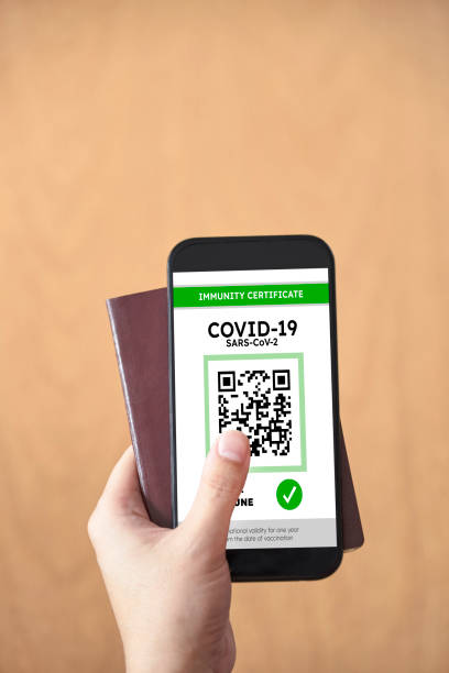 istock Hand holding a passport and a smartphone with a Covid19 immunity certificate 1314399235