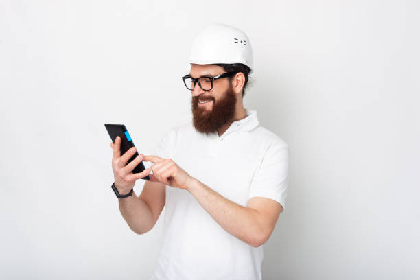 istock Young man wearing a protection hard hat is looking at his tablet. 1314402240