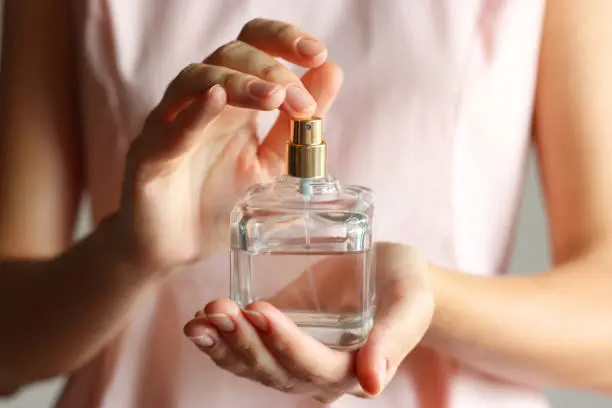 Photo of The girl uses perfume. Perfume in female hands.