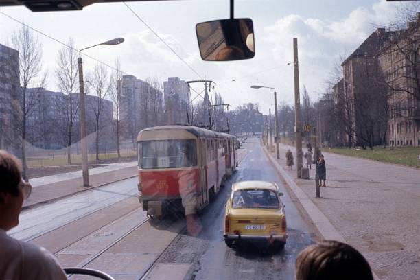 Dresden, Saxony, Germany (GDR), 1985. Street scene in a new housing estate in Dresden seen from a tourist bus with a tram, prefabricated buildings, pedestrians and a Russian Orthodox church in the background.