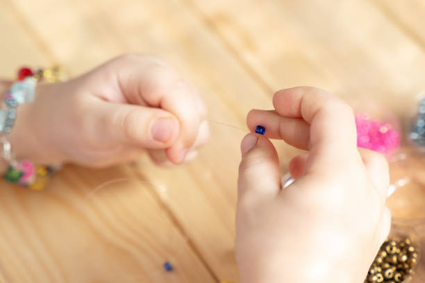 istock The child makes jewelry with his own hands, stringing colorful beads on a thread 1314405209