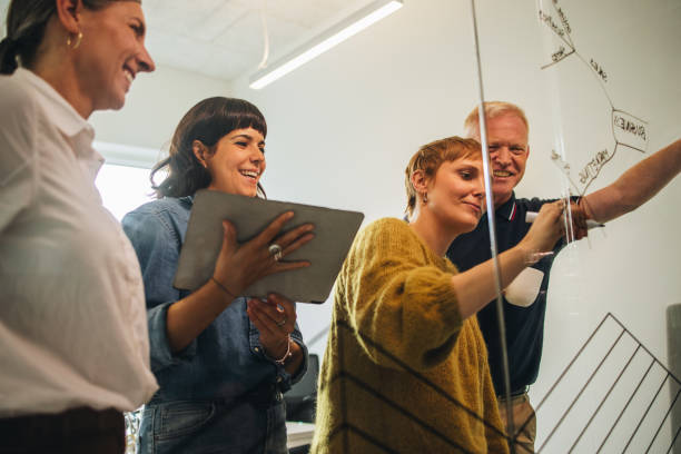istock Businesswoman plotting out details on a glass wall with colleagues 1314406764