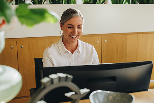 Receptionist working on computer. Mature woman working at front desk.