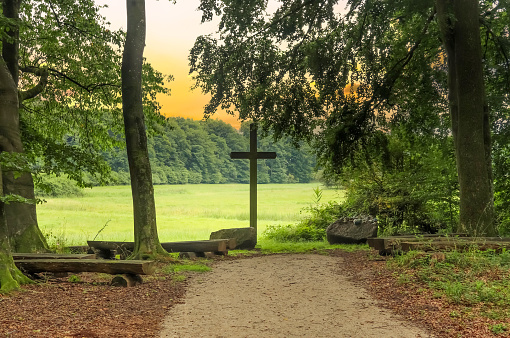 A religious wooden cross in a small forest in Europe.