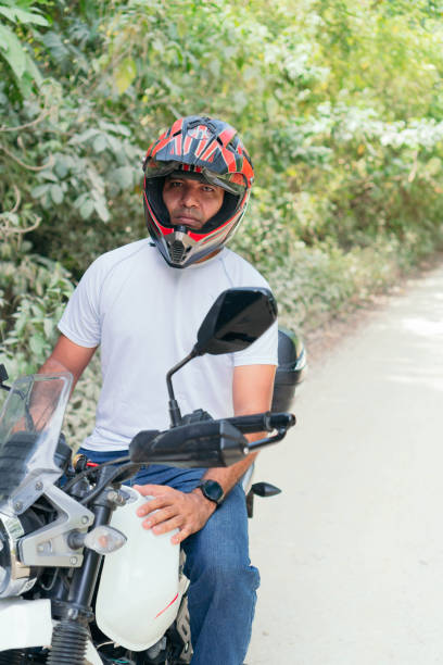 istock Young man with his motorcycle parked on a country road 1314412984