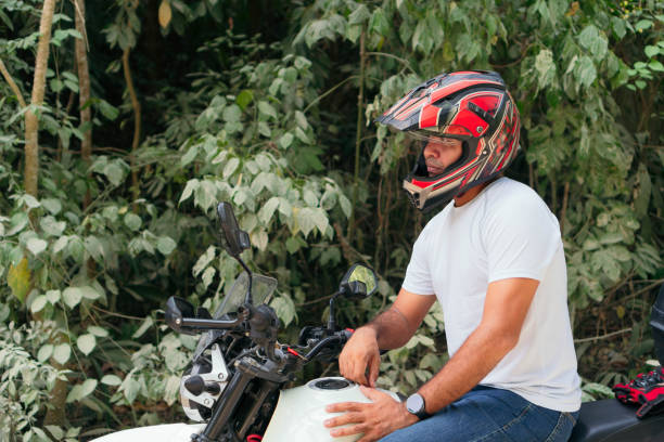istock Young man with his motorcycle parked on a country road 1314413037