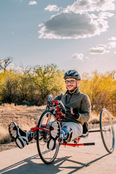 istock Handsome Young Man Riding a Red Handcycle Wearing Orthotic Leg Braces for Adaptive Exercise Outdoors at Sunset 1314422818