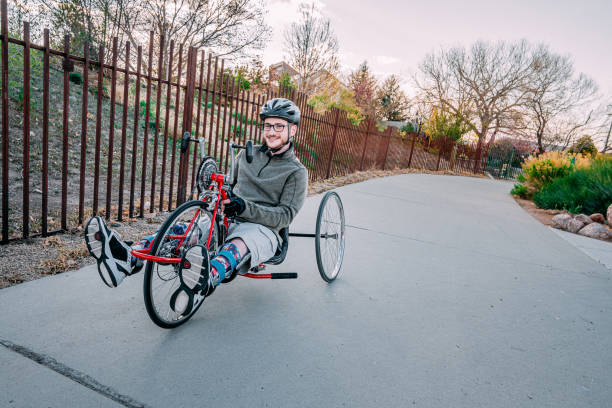 istock Handsome Young Man Smiling and Looking at the Camera while Sitting on His Red Handcycle Wearing Orthotic Leg Braces for Adaptive Exercise on the Trail 1314422922
