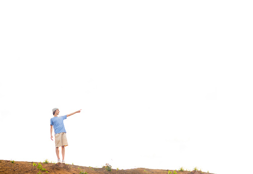 Young man at the top of a mountain pointing his finger. Large space for writing
