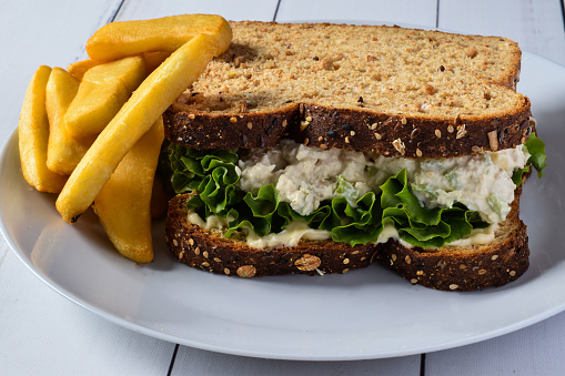 chicken salad sandwich with lettuce and mayonnaise served with fries,
