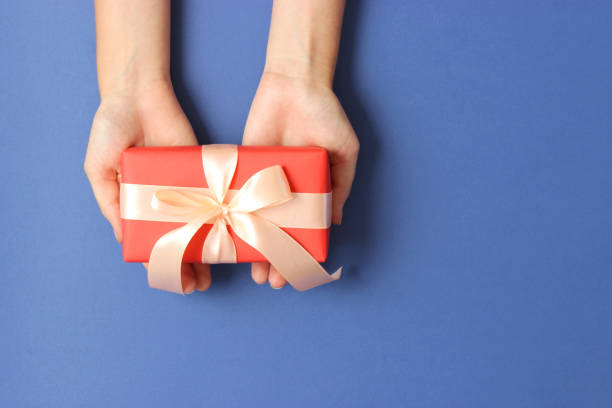 istock gift in female hands on a colored background top view. 1314428946