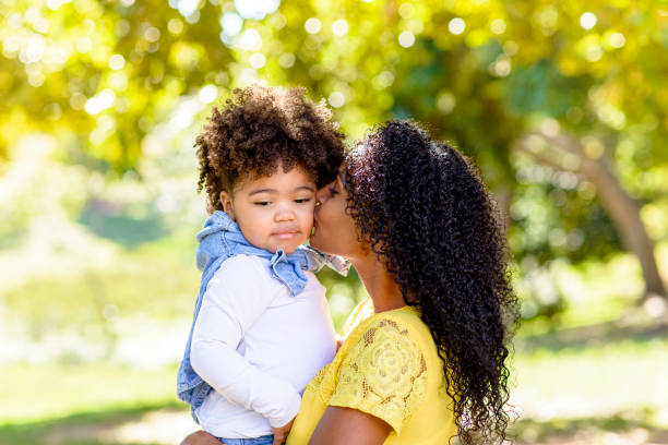 istock Mother kissing daughter's face during walk in park 1314429135