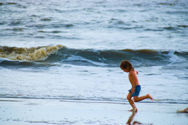 A Little Girl Running on the Beach Seascape. A little girl is running on the beach, waves as background. Created in Golden Isles, Georgia, August 23, 2020 saint simons island photos stock pictures, royalty-free photos & images