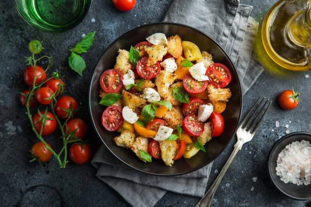 panzanella, geleneksel i̇talyan domatesi, mozzarella ve siyah kasede ekmek salatası - kruton stok fotoğraflar ve resimler