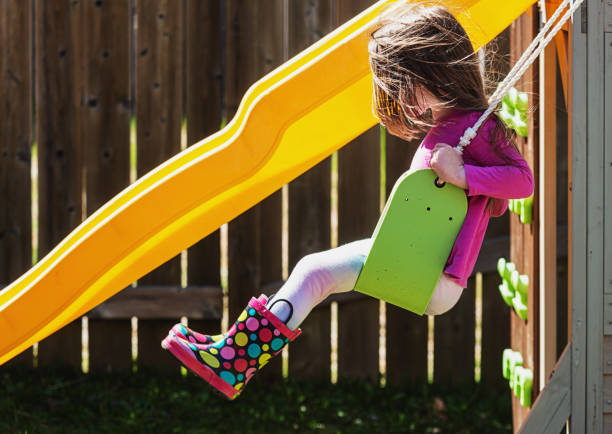 Girl Enjoys Swinging on Her Backyard Playground