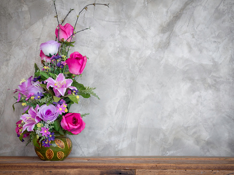 Beautiful colorful bouquet flowers in the vintage vase decoration on wooden table on loft-style concrete wall background with copy space.