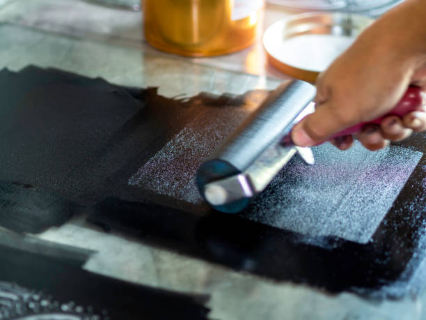 Printmaking tool in art studio. Motion blur of the artist hand, printmaker rolling a printmaking roller with black relief ink color in the art studio, close up. Linocut, woodcut, etching and silkscreen art printing step process. monoprint stock pictures, royalty-free photos & images