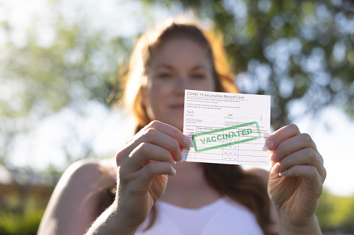 A woman holding her proof of Vaccination card